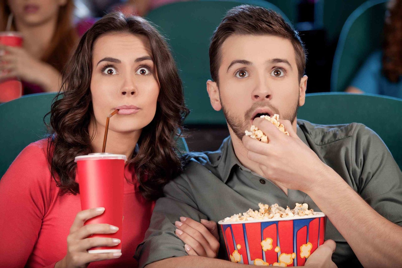 Гляди кинофильмы. Попкорн в кинотеатре. Удвиление в кинотеатре. Люди едят попкорн в кинотеатре.
