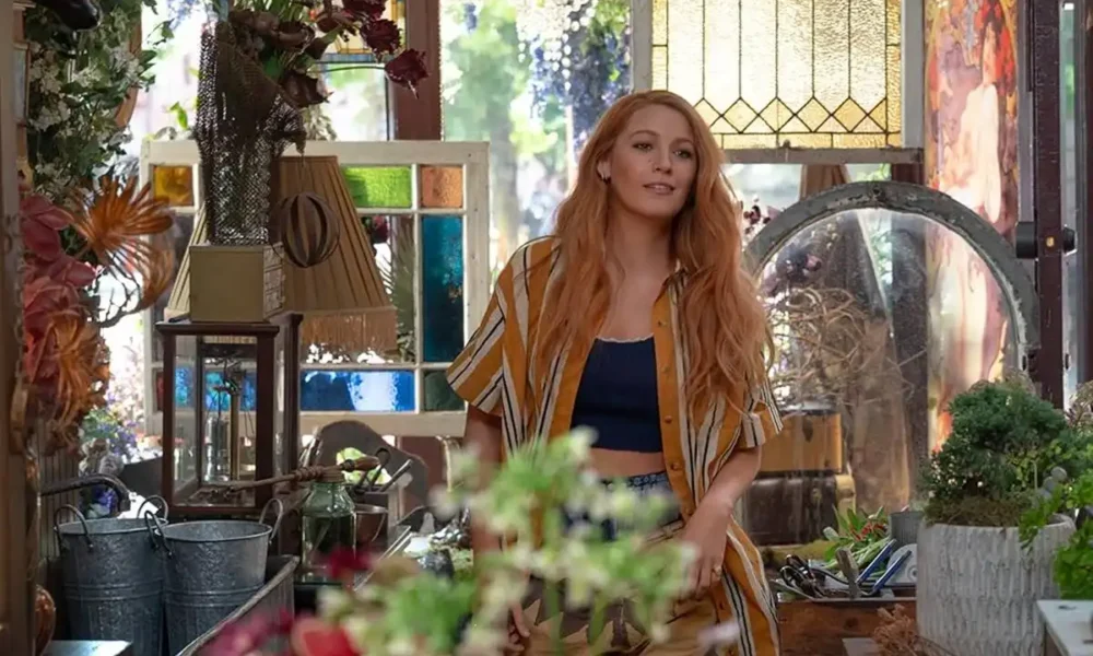 Blake Lively interpretando protagonista de "É Assim Que Acaba" (2024), da Sony Pictures. Personagem está em o que parece ser uma pequena estufa, uma sala com várias plantas dentro de casa.