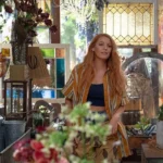 Meninas Malvadas | Jonathan Bennet quer Reunir Lindsay Lohan e Lacey Chabert em Filme de Natal Blake Lively interpretando protagonista de "É Assim Que Acaba" (2024), da Sony Pictures. Personagem está em o que parece ser uma pequena estufa, uma sala com várias plantas dentro de casa.