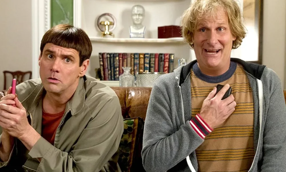 Debi e Lóide, protagonistas de filme homônimo, sentados em um sofá. Há uma estante atrás deles.