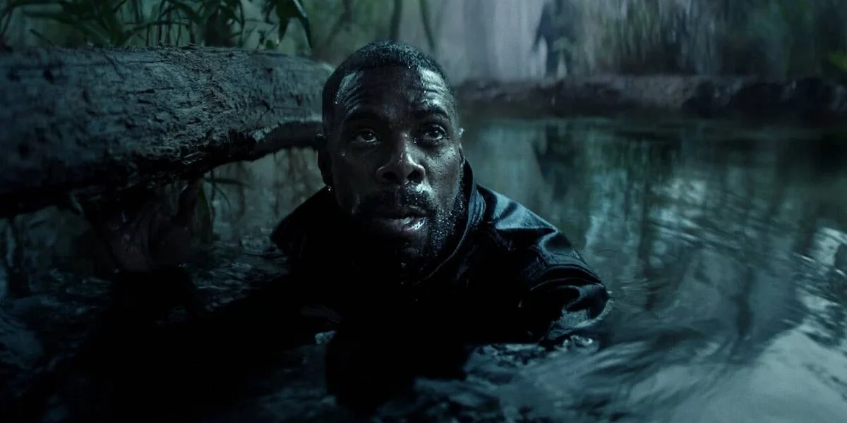 Jesse L. Martin interpretando Alec Baker, protagonista de Irracional. Personagem está com o corpo submerso até o pescoço em um aparente lago. Uma figura sombria, embaçada, está atrás dele, na margem.