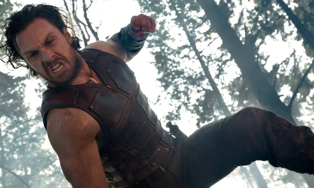 Aaron Taylor-Johnson como "Kraven, o Caçador", em filme homônimo de 2024. O anti-herói está dando socos em alguém, a câmera é vista de baixo para cima.