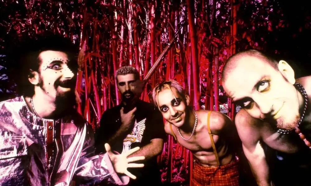Imagem de divulgação dos 26 anos da banda System of a Down, com uma foto, em paleta vermelha, dos integrantes à época do debut.