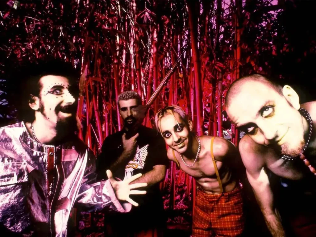 Imagem de divulgação dos 26 anos da banda System of a Down, com uma foto, em paleta vermelha, dos integrantes à época do debut.