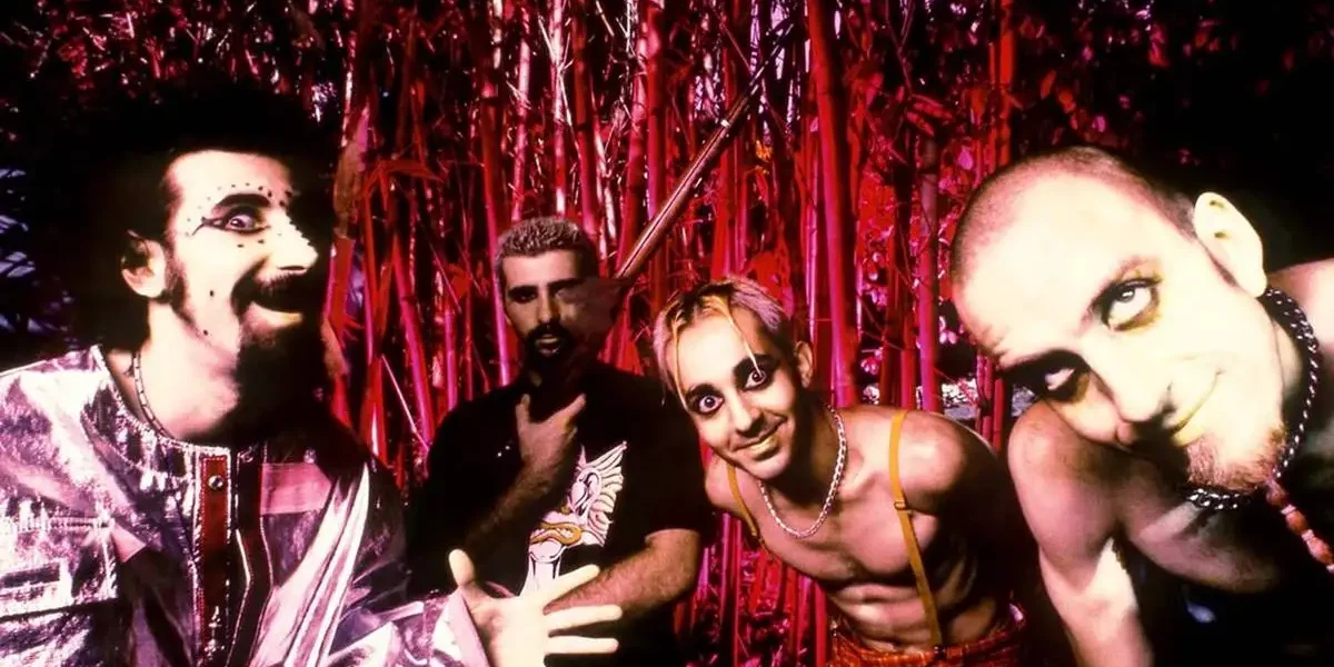 Imagem de divulgação dos 26 anos da banda System of a Down, com uma foto, em paleta vermelha, dos integrantes à época do debut.