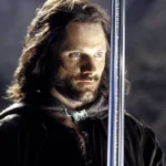 CCXP24 | Os Estandes Mais Incríveis Que Você Precisa Visitar Viggo Mortensen como Aragorn em "O Senhor dos Anéis". O personagem está com uma expressão séria e encarando um ponto distante na tela, com a espada na frente de seu peito. Imagem para a matéria de "The Hunt for Gollum".