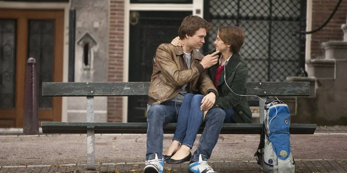 Sessão da Tarde Hoje | Saiba Qual Filme Será Exibido Nesta Segunda-feira, 27 de Janeiro Personagens de "A Culpa é das Estrelas", filme de 2014: Augustus Waters (Ansel Elgort) e Hazel Grace Lancaster (Shailene Woodley), respectivamente à esquerda e direita. Ela está com aparelhos para ajudarem-na a respirar e ele segura o queixo dela de maneira carinhosa. Ambos estão sentados em um banco ao ar livre.