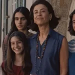 Fernanda Torres interpretando Eunice Paiva em "Ainda Estou Aqui", cercada por seus filhos e sorrindo para uma foto.