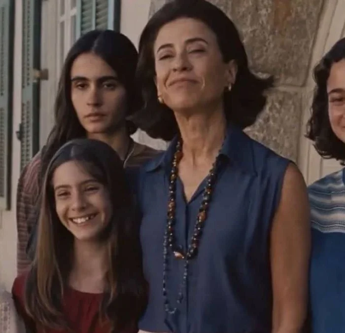 Fernanda Torres interpretando Eunice Paiva em "Ainda Estou Aqui", cercada por seus filhos e sorrindo para uma foto.