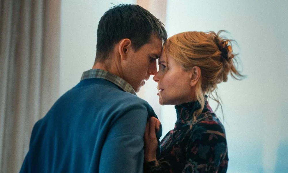 Samuel (Harris Dickinson) e Rony (Nicole Kidman), respectivamente à esquerda e direita, centralizados na câmera. Ela puxa-o pela blusa e suas testas estão se encostando.