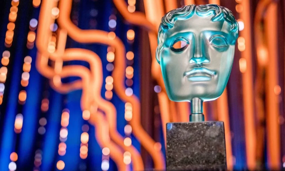 Imagem promocional para o BAFTA 2025, com um troféu em destaque à direita e um palco iluminado de azul e fios amarelos por trás.