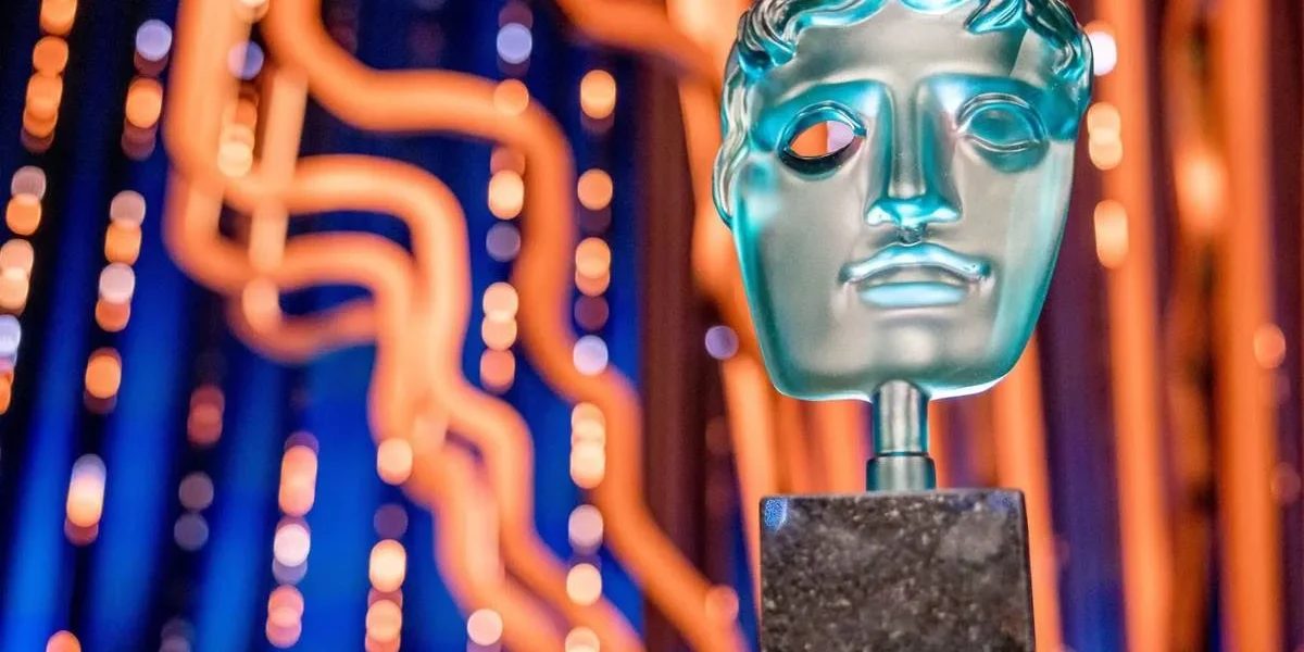 BAFTA 2025 | Emília Pérez vence Ainda Estou Aqui em Filme Estrangeiro e Conclave é o Melhor Filme Imagem promocional para o BAFTA 2025, com um troféu em destaque à direita e um palco iluminado de azul e fios amarelos por trás.
