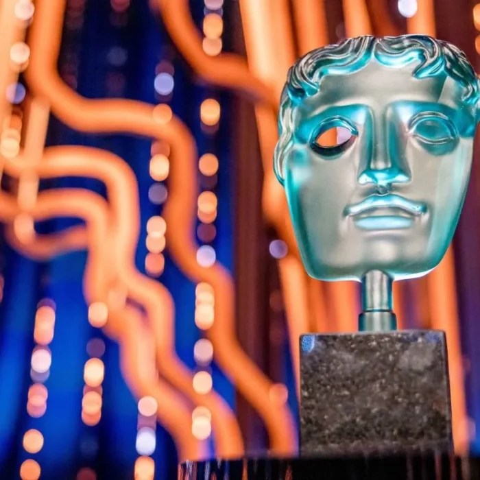 Imagem promocional para o BAFTA 2025, com um troféu em destaque à direita e um palco iluminado de azul e fios amarelos por trás.