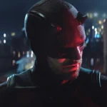 Charlie Cox como Matt Murdock, o Demolidor, em "Demolidor: Renascido". Personagem está uniformizado, focado pela câmera, e desvia o olhar olhando para baixo à direita.