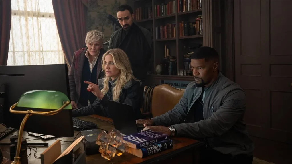 De Volta à Ação (2025) | Filme é Uma Checklist da Ação Genérica 2 Grupo de espiões de "De Volta a Ação" (2025), Netflix, em uma escritório. Cameron Diaz e Jamie Foxx em destaque interpretando seus personagens.