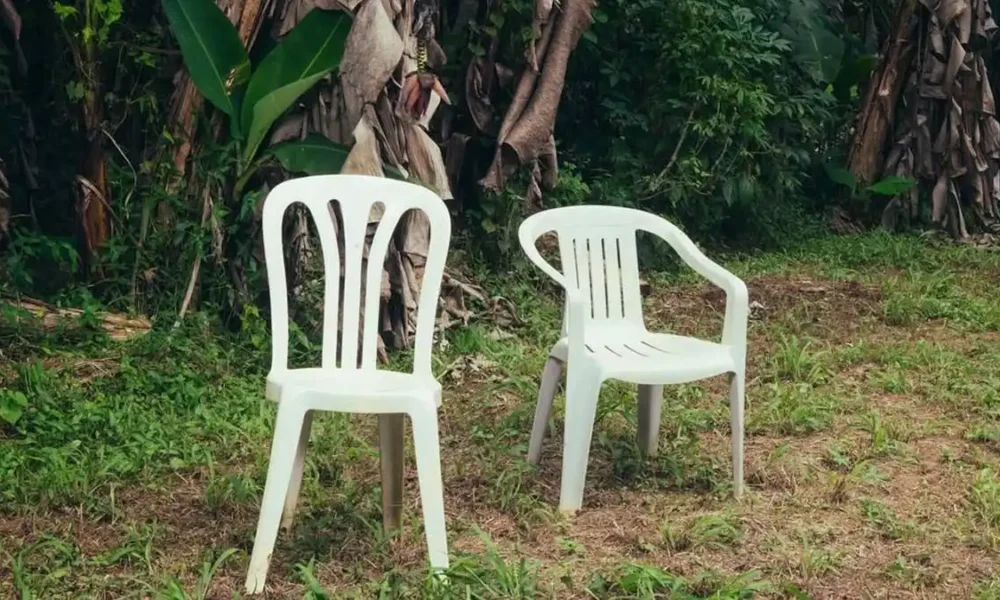 Duas cadeiras de plástico em um quintal de casa de família. Há bananeiras ao fundo. Capa do álbum "Debí Tirar Más Fotos" (2025), de Bad Bunny.