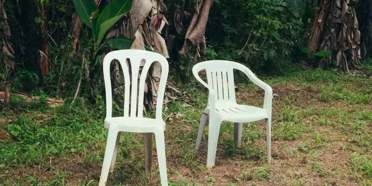 Duas cadeiras de plástico em um quintal de casa de família. Há bananeiras ao fundo. Capa do álbum "Debí Tirar Más Fotos" (2025), de Bad Bunny.