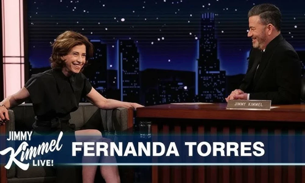 Thumbnail do YouTube da entrevista da Fernanda Torres no "Jimmy Kimmel Live!". Atriz está sentada no sofá, com o entrevistador em uma mesa, sentado à direita.