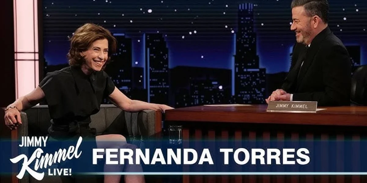 Thumbnail do YouTube da entrevista da Fernanda Torres no "Jimmy Kimmel Live!". Atriz está sentada no sofá, com o entrevistador em uma mesa, sentado à direita.