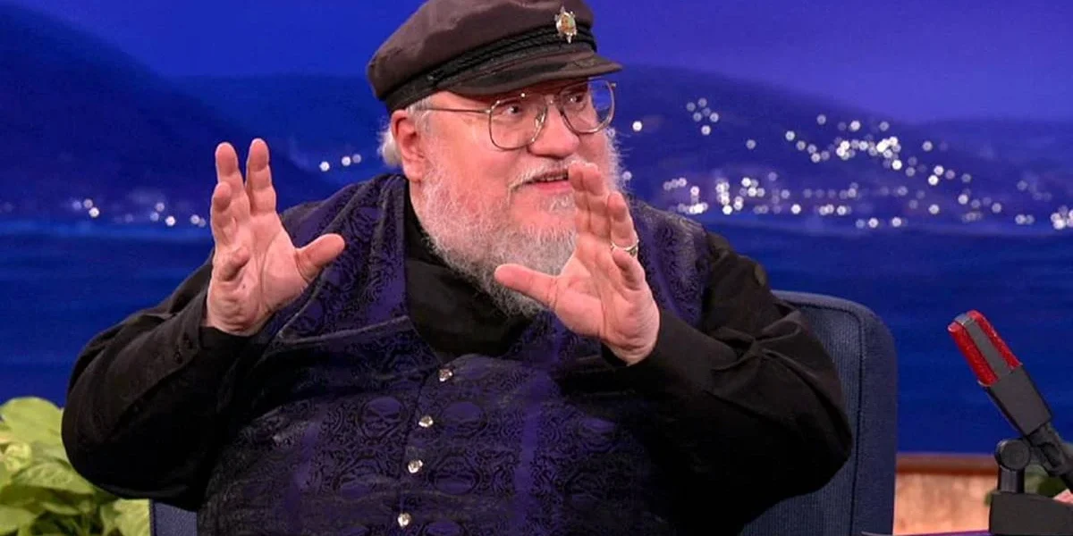George R. R. Martin em entrevista, sorrind oe gesticulando.