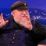 George R. R. Martin em entrevista, sorrind oe gesticulando.