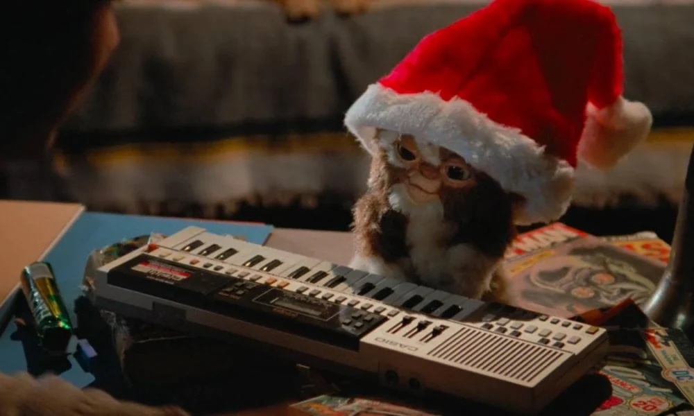 Gremlin não monstrificado e com gorro de natal frente a um teclado. Imagem direta do filme "Gremlins" (1984).