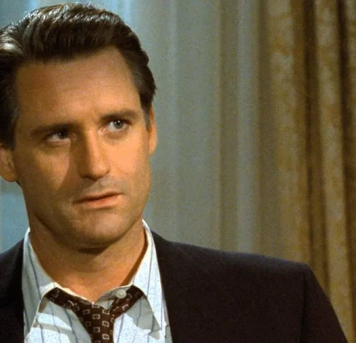 Bill Pullman como o presidente de Independence Day (1996). Há uma bandeira dos EUA ao seu fundo, à direita.