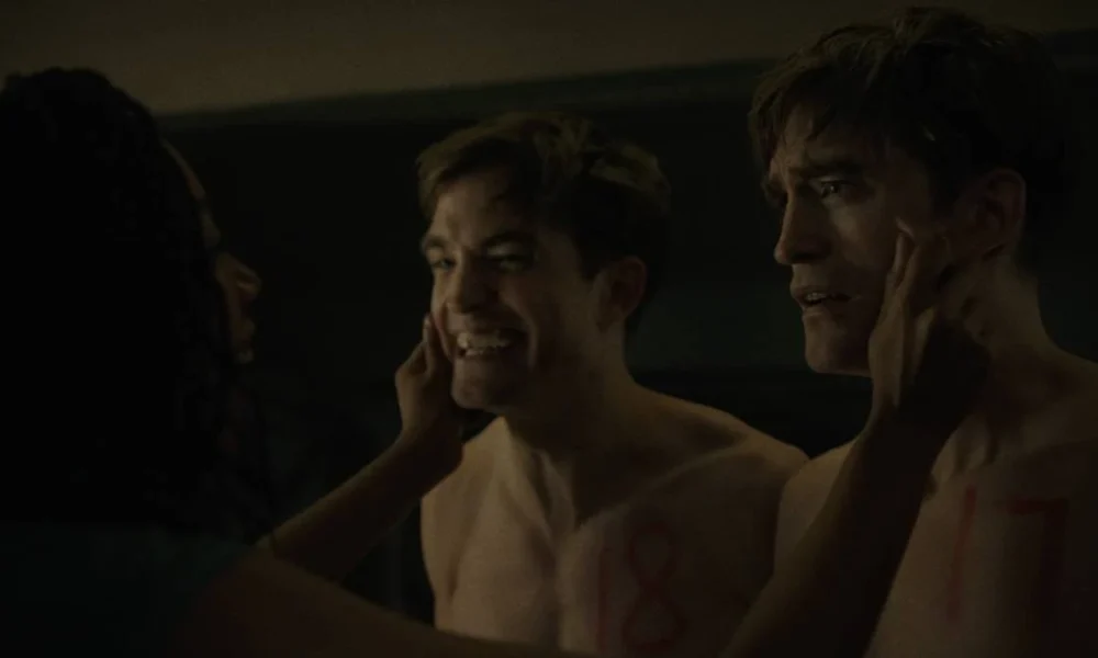 Mickey 17 | Confira Teaser de novo Filme de Bong Joon Ho com Robert Pattinson Robert Pattinso como o protagonista de "Mickey 17". Ele está sem camisa nas duas versões, a esquerda, o número 18, sorri de forma estranha e quase desesperada, a da direita, o Mickey 17, está assustada. Naomi Ackie (Nasha Adjaya) aberta a bochecha dos dois.