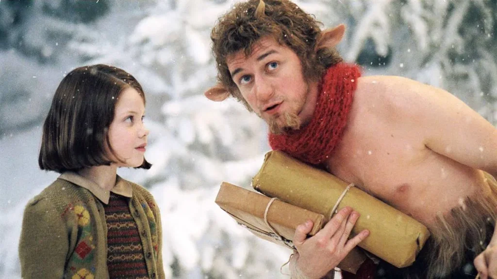 10 Finais Mais Odiados de Todos os Tempos: Do Luxo ao Lixo 4 Lucy, à esquerda, a caçula dos Pevensie, olhando para o fauno Tumnus, com um cachecol, carregando rolos de pergaminho e de corpo curvado. Atrás deles há uma paisagem nevada.