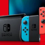 Imagem do console base Nintendo Switch, na cor azul e vermelha, demonstrando sua funcionalidade em conectar-se com televisores, com uma televisão ao fundo.