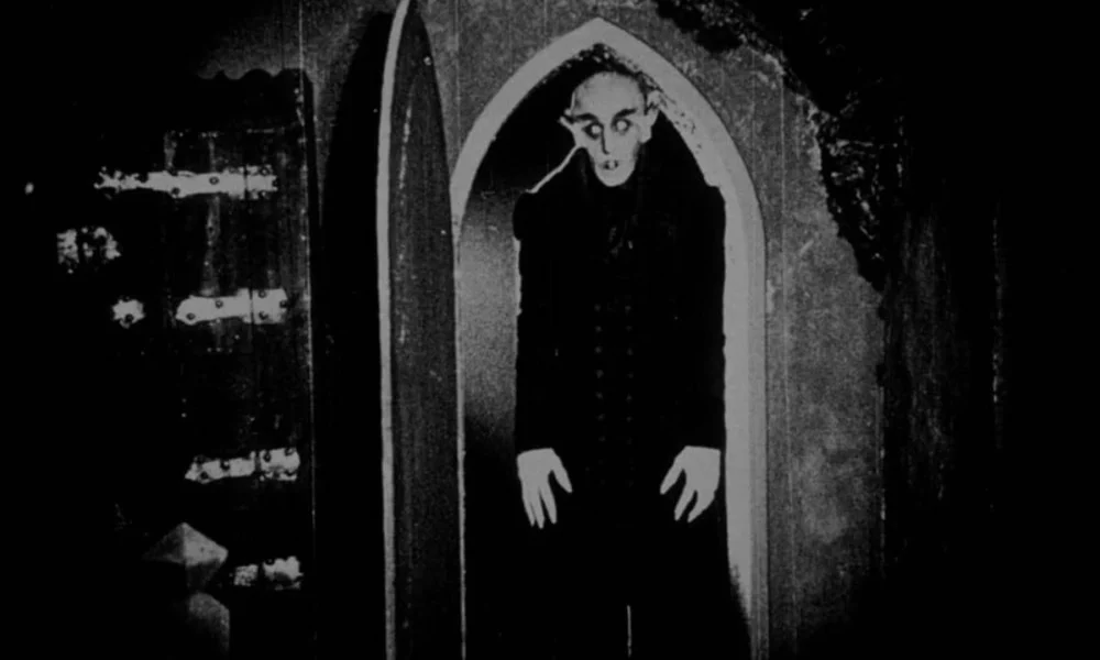 Max Schreck em icônica cena de Nosferatu, com o vampiro Conde Orlok na porta.