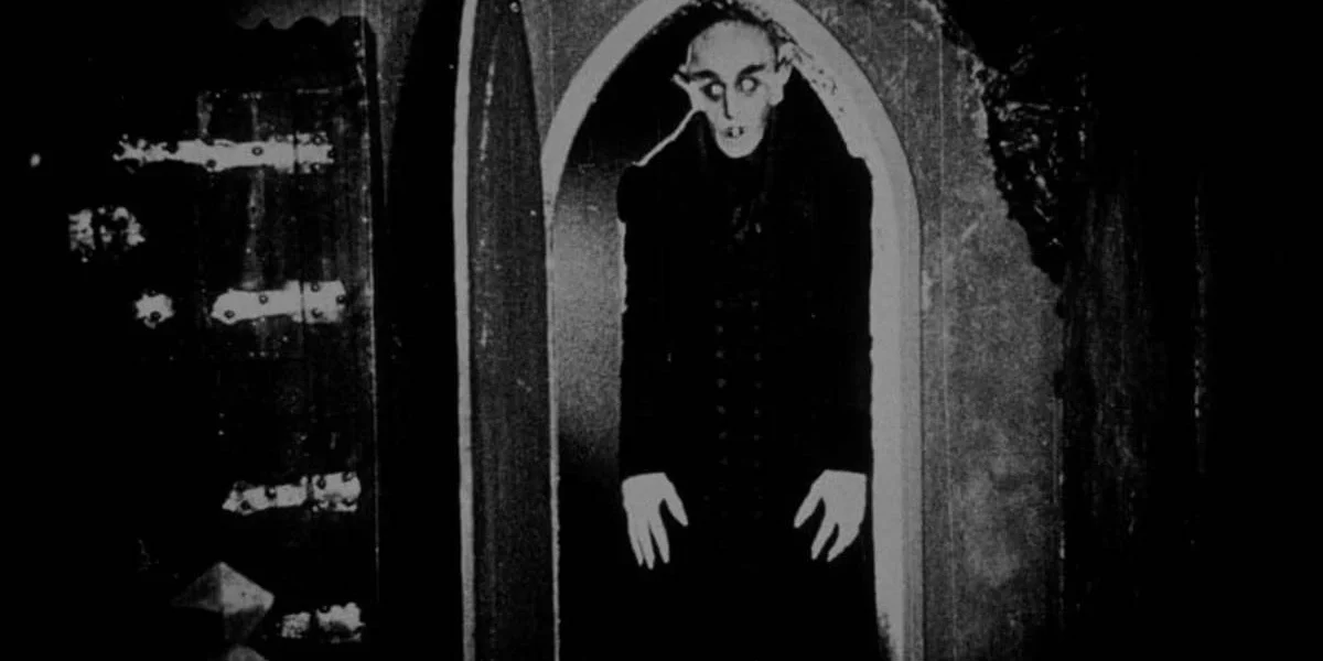 Max Schreck em icônica cena de Nosferatu, com o vampiro Conde Orlok na porta.