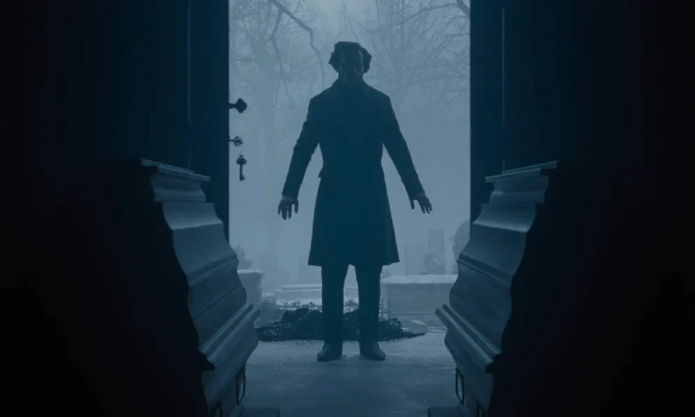 Porta aberta, com silhueta ao fundo, e dois caixões em destaque, no longa "Nosferatu" (2024), de Eggers.