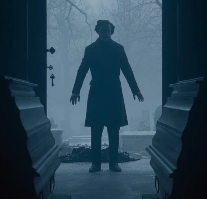 Porta aberta, com silhueta ao fundo, e dois caixões em destaque, no longa "Nosferatu" (2024), de Eggers.