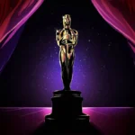 Conclave | Filme Dispara na Prime Video Após Morte do Papa Francisco Imagem promocional dos prêmios Oscar, com a estatueta em um fundo roxo, com cortinas na paleta de cores simulando o teatro da premiação.