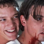Stu e Billy, os atores Matthew Lillard e Skeet Ulrich, respectivamente à esquerda e direita, no filme "Pânico" (1996). Stu está sorrindo maniacamente sobre o ombro direito de Billy, que está com o pescoço ensanguentado.