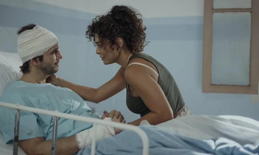 Vladimir Brichta e Juliana Paes como Tomás e Liana na novela/série "Pedaço de Mim", 2024, destaque do Prêmio APCA 2024. Personagens estão em hospital, Tomás cheio de faixas, com roupas hospitalares, e em uma maca, com Liana fazendo carinho perto em seu rosto.