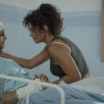 Vladimir Brichta e Juliana Paes como Tomás e Liana na novela/série "Pedaço de Mim", 2024, destaque do Prêmio APCA 2024. Personagens estão em hospital, Tomás cheio de faixas, com roupas hospitalares, e em uma maca, com Liana fazendo carinho perto em seu rosto.