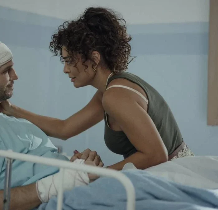 Vladimir Brichta e Juliana Paes como Tomás e Liana na novela/série "Pedaço de Mim", 2024, destaque do Prêmio APCA 2024. Personagens estão em hospital, Tomás cheio de faixas, com roupas hospitalares, e em uma maca, com Liana fazendo carinho perto em seu rosto.