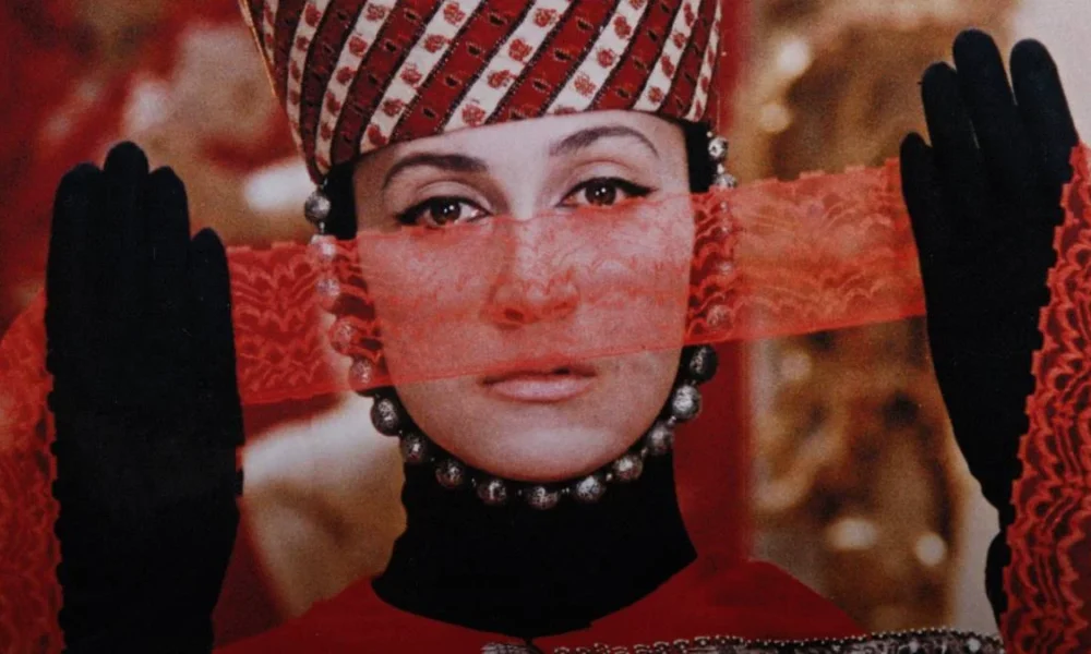 Mulher com vestes típicos armênios, segurnado um véu vermelho como parte de sua roupa. Cena de "The Color of Pomegranates" (1969).