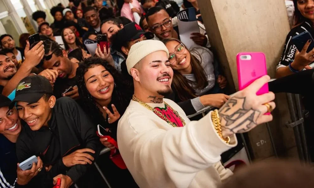 Jottapê em encontro com fãs da série "Sintonia", tirando uma selfie com celular de fã.