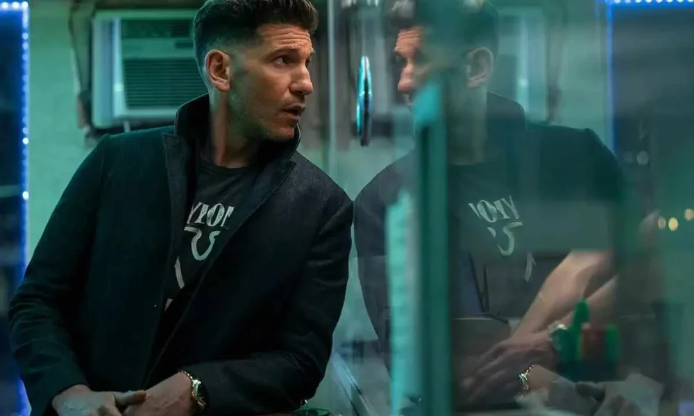 Ben Affleck olhando através de um vidro em "O Contador 2". Vidro reflete sua imagem.