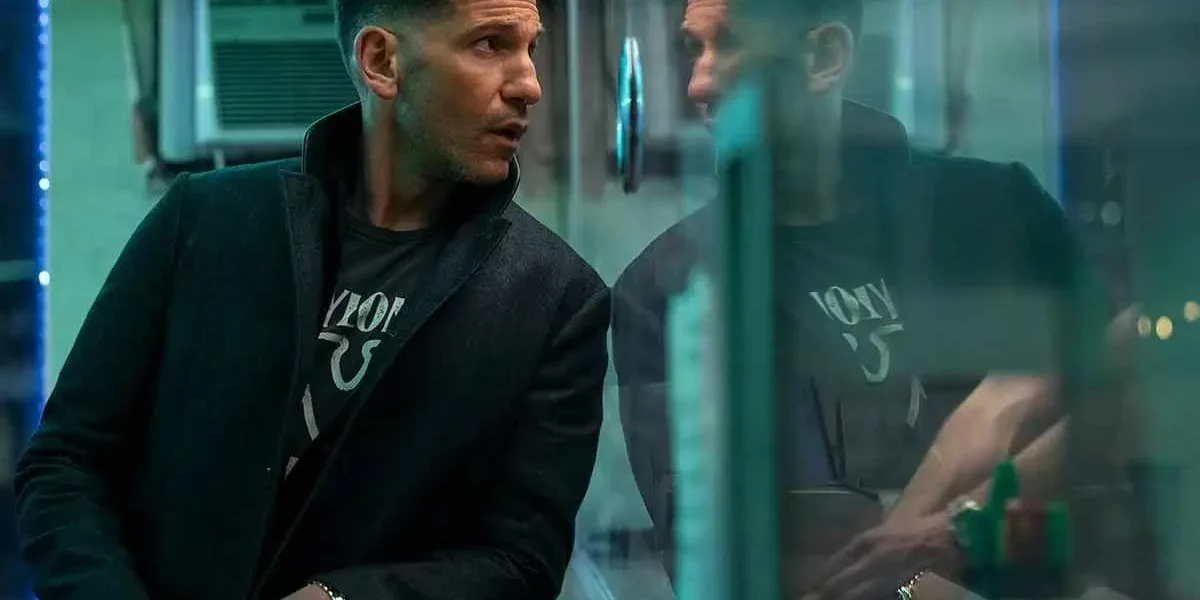 Ben Affleck olhando através de um vidro em "O Contador 2". Vidro reflete sua imagem.