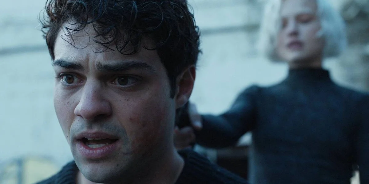 Noah Centineo como o protagonista de "O Recruta", na temporada 2, com uma arma apontada até ele por uma mulher loira.