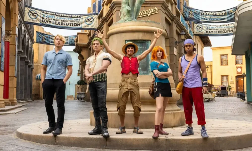 Sanji, Zoro, Luffy, Nami, e Usopp do live-action da Netflix em primeira imagem da segunda temporada. Membros do elenco estão em uma cidade cenográfica controlada pela marinha.