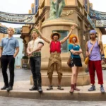 Sanji, Zoro, Luffy, Nami, e Usopp do live-action da Netflix em primeira imagem da segunda temporada. Membros do elenco estão em uma cidade cenográfica controlada pela marinha.