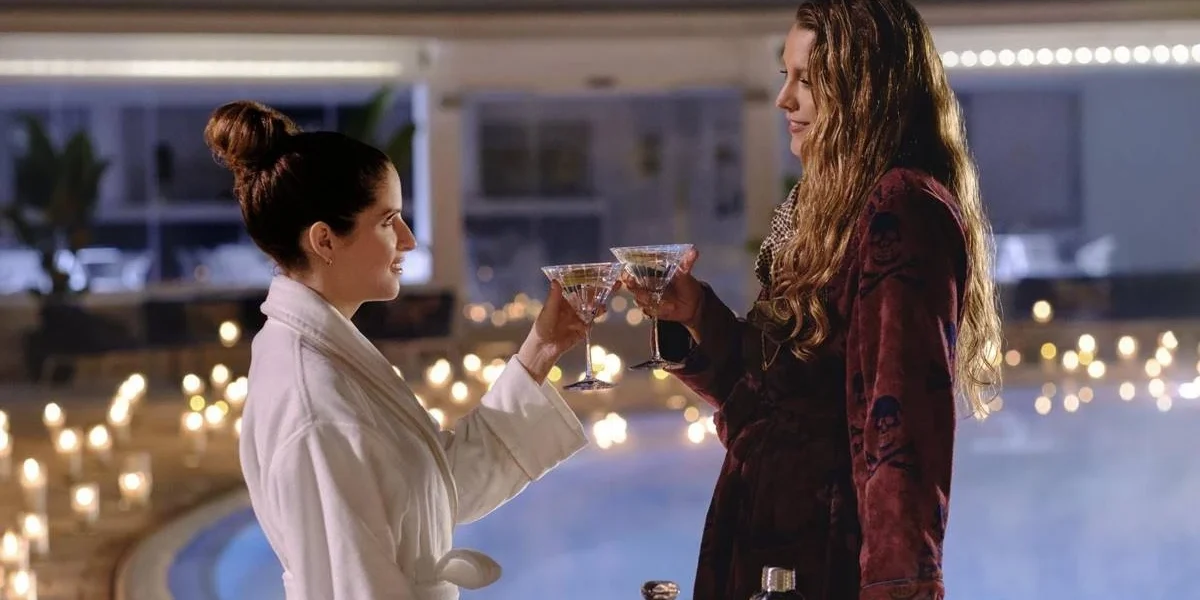 Outro Pequeno Favor | Saiu Primeiro Trailer com Anna Kendrick e Blake Lively Anna Kendrick e Blake Lively como Stephanie Smothers e Emily Nelson, protagonistas de "Outro Pequeno Favor". Elas estão em se olhando, brindando com as mãos próximas uma da outra, tomando um drink, em um lugar luxuoso desfocado ao fundo.