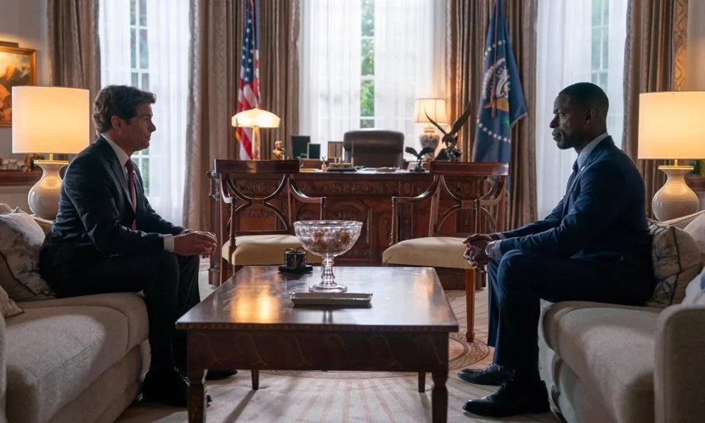 O Presidente Cal Bradford, à esquerda, e o protagonista Xavier Collins, à direita, interpretados por James Marsden e Sterling K. Brown, respectivamente, conversando cara a cara em sofás diferentes no Salão Oval da Casa Branca na série "Paradise", primeiro episódio da primeira temporada.