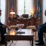 O Presidente Cal Bradford, à esquerda, e o protagonista Xavier Collins, à direita, interpretados por James Marsden e Sterling K. Brown, respectivamente, conversando cara a cara em sofás diferentes no Salão Oval da Casa Branca na série "Paradise", primeiro episódio da primeira temporada.