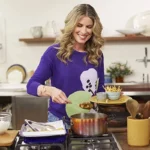 MasterChef | Sem Apresentador, Programa Mudará Formato em 2025 Rita Lobo em uma cozinha cheia, com uma blusa roxa, sorrindo, apresentando o "Cozinha Prática", do GNT.